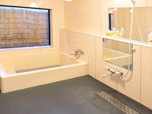 a bathroom with a bath tub and a window at ゲストハウス星風 in Suo Oshima