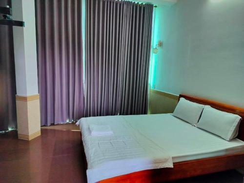 a bedroom with a bed and a window with purple curtains at Nhật Linh Homestay in Hue