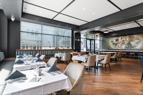 a restaurant with white tables and chairs and a large window at Hotel Indigo Baton Rouge Downtown by IHG in Baton Rouge