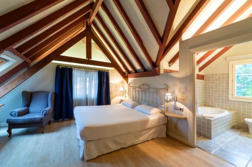 a bedroom with a bed and a tub and a chair at KAIAN MAITEA in Plentzia