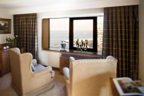 a living room with two chairs and a view of the ocean at Mövenpick Hotel Izmir in Izmir