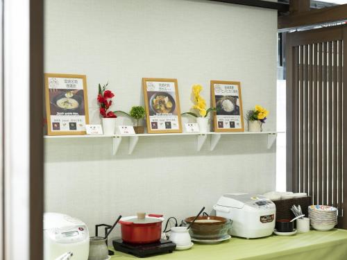 a kitchen counter with shelves with pictures and flowers at Hotel Wing International Miyakonojo in Miyakonozyō