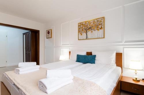 a bedroom with a large bed with white sheets and blue pillows at Hotel Royal Plaza By TimHotels in Timişoara