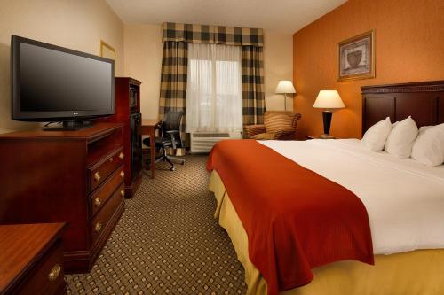 a hotel room with a bed and a flat screen tv at Holiday Inn Express & Suites by IHG Chambersburg by IHG in Chambersburg
