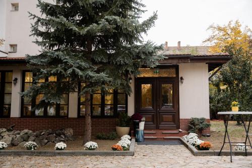 a house with a tree and flowers in front of it at Hotel Royal Plaza By TimHotels in Timişoara
