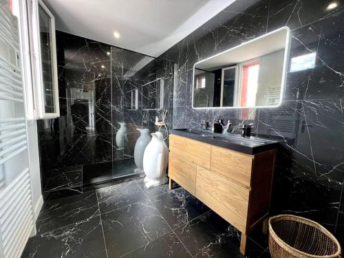uma casa de banho preta com um lavatório e um espelho em Superbe Appartement avec terrasse em Libourne