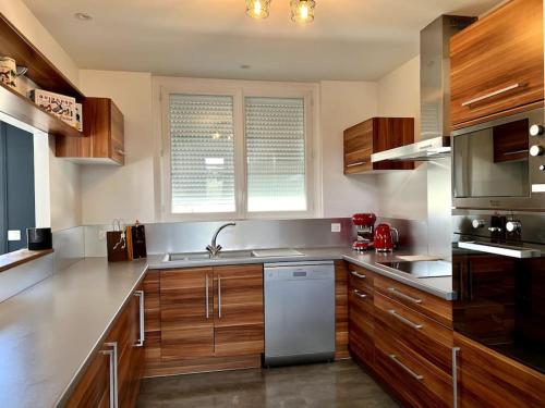 une cuisine avec des armoires en bois et des appareils en acier inoxydable dans l'établissement Superbe Appartement avec terrasse, à Libourne