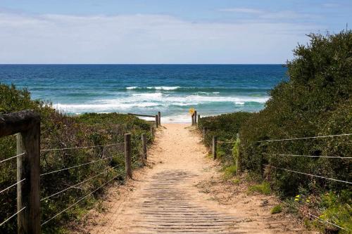 a dirt path leading down to the beach at Mona Vale Surf to Tee in Mona Vale
