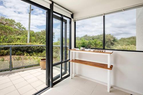a bathroom with large windows and a view of the forest at Mona Vale Surf to Tee in Mona Vale