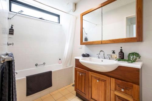 a bathroom with a sink and a tub and a mirror at Mona Vale Surf to Tee in Mona Vale