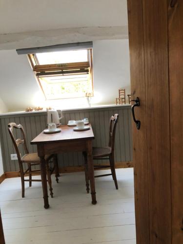 a table and chairs in a kitchen with a window at La Chambrette La Canopée du Mont in Saint-Georges-de-Reintembault