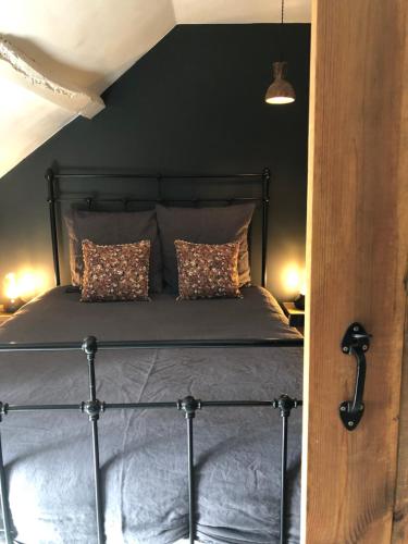 a bedroom with a black bed with two pillows at La Chambrette La Canopée du Mont in Saint-Georges-de-Reintembault