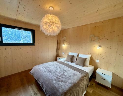 une chambre avec un grand lit et un lustre dans l'établissement Chalet des Freinets : proche centre de Châtel et au calme, à Châtel