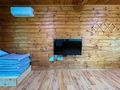 a room with a wooden wall with a flat screen tv at Pyeongchang The Meomum Pension in Pyeongchang 