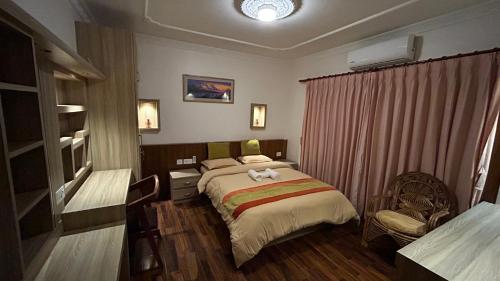 a bedroom with a bed and a chair in it at Raniban Suites - Apartment Home in Kathmandu
