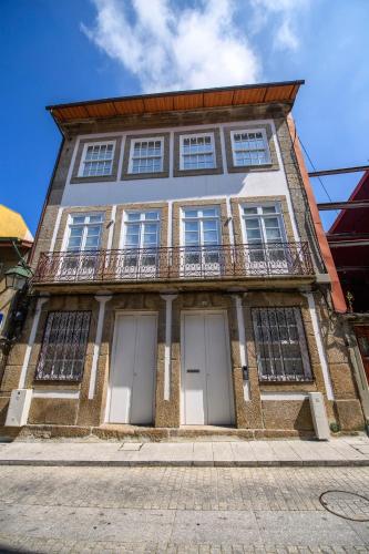 a tall building with three doors and a balcony at Maria de Lurdes Residências in Guimarães