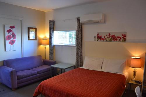 a hotel room with a bed and a blue couch at McWilliam Apartments in Christchurch