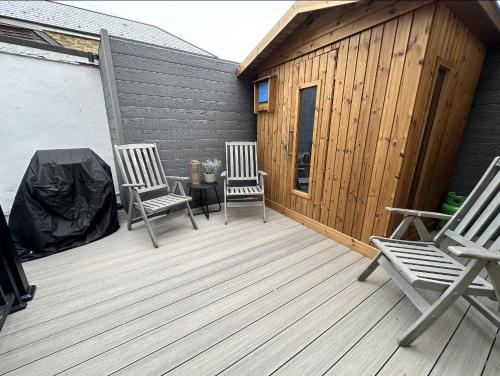 two chairs on a wooden deck with a building at Central Margate house with sauna & private garden in Kent
