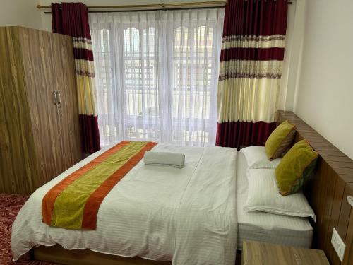a bedroom with a large bed with a window at Raniban Suites - Apartment Home in Kathmandu