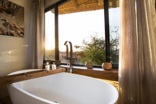 a bath tub in a bathroom with a window at Klaserie Drift Misava in Klaserie Private Nature Reserve