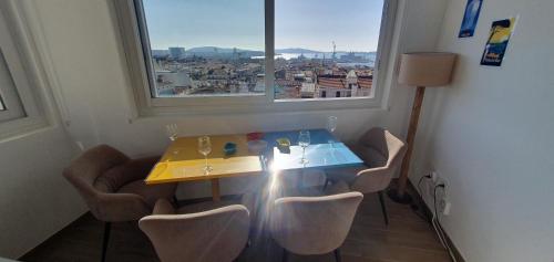 - une table avec des chaises dans une chambre avec une fenêtre dans l'établissement Stunning Sea View, Steps from Station and Port - Vue imprenable sur la mer, à quelques pas de la gare et du port, à Toulon