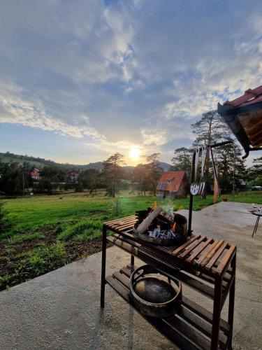 a park bench sitting in a park with the sun setting at Skroviste, Zlatibor-Vodice in Zlatibor