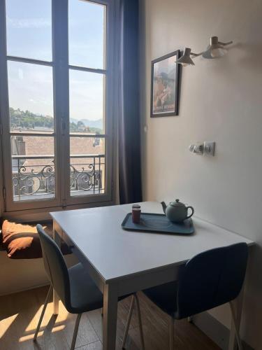 une table et des chaises dans une pièce avec une fenêtre dans l'établissement Le Centr’Aix-Studio au cœur d’Aix-les-Bains, à Aix-les-Bains