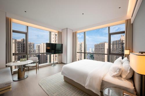 a bedroom with a large white bed and a large window at Qinglian Jinghe Hotel Wuhan Zoo International Expo Center Branch in Han-yang-hsien
