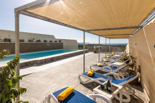 a row of lounge chairs on the roof of a building with a pool at Ta'Battista B&B with pool - Gozo in Xewkija