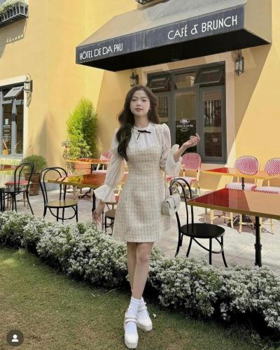 a woman in a dress standing in front of a restaurant at Hôtel De Da Phu in Da Lat