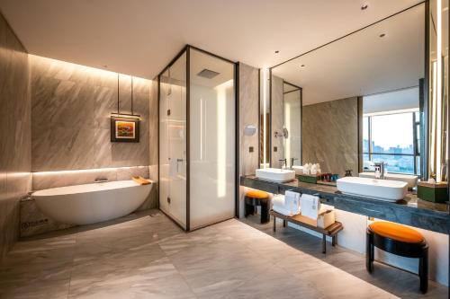 a bathroom with two sinks and a tub and mirrors at Qinglian Jinghe Hotel Wuhan Zoo International Expo Center Branch in Han-yang-hsien