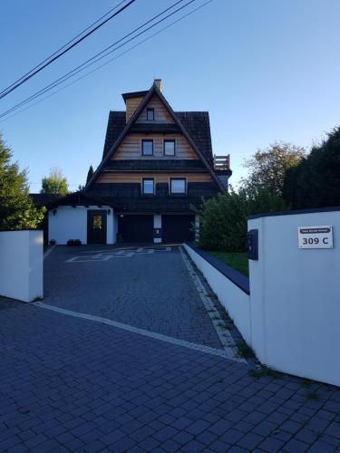 a house with a stone driveway in front of a building at Dom Górski Klimat-Willa 160 m2 z wewnętrzną sauną fińską in Zakopane