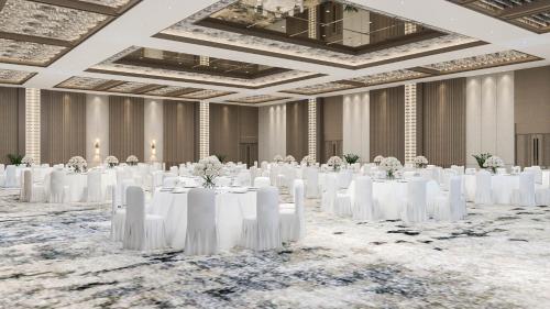 un salón de baile con mesas blancas y sillas blancas en Labersa Hotel & Convention Center Samosir, en Sinapuran