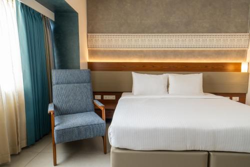 a bedroom with a bed and a blue chair at Shilton Dee Cee in Chennai