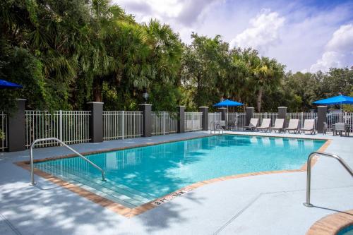 a swimming pool at a resort with chairs and umbrellas at Holiday Inn Express & Suites Bradenton East-Lakewood Ranch by IHG in Lakewood Ranch