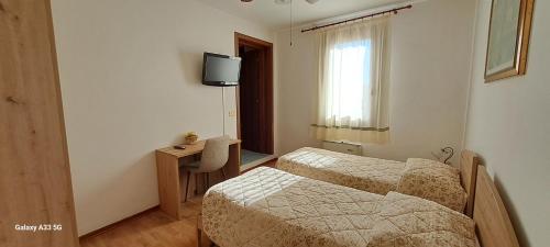 a room with two beds and a desk and a television at La Pioppa Agriturismo in Sacile