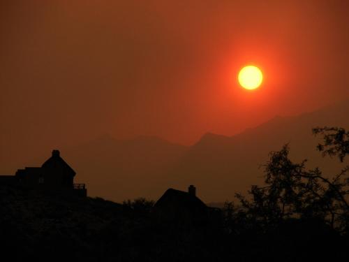 a sun setting over a hill with houses in the foreground at Bosch Luys Kloof Nature Reserve in Ladismith
