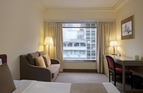 una camera d'albergo con un letto, una scrivania e una finestra di Prudential Hotel a Hong Kong