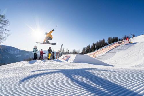 a person jumping in the air on a snowboard at Hotel Trattlerhof in Bad Kleinkirchheim