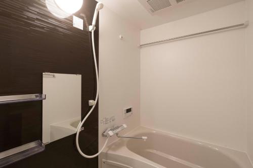 a bathroom with a white tub and a shower at Rufura Fukusima in Osaka