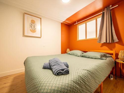 a bedroom with orange walls and a bed with two pillows at L'Évasion Sauna & Spa in Saint-Rambert-dʼAlbon