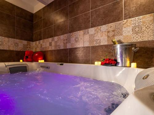a bath tub filled with blue water in a bathroom at L'Évasion Sauna & Spa in Saint-Rambert-dʼAlbon