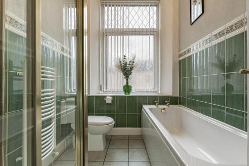 a bathroom with a tub and a toilet and a window at Old Mart View in Hawick