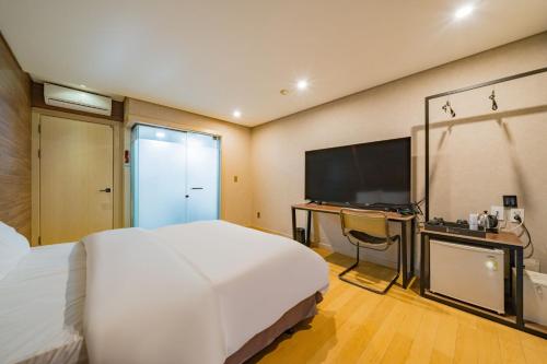 a bedroom with a large white bed and a television at Incheon Airport Hotel Seattle in Incheon