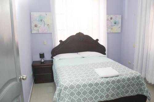 a bedroom with a bed with a wooden headboard and a window at Mansión familiar capítulo con piscina y cerca de la playa in La Belleza
