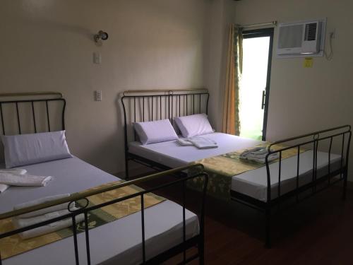 two twin beds in a room with a window at Rufina's Leisure Center in Tagum