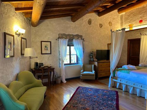 a bedroom with a bed and a chair and a tv at Relais La Magioca -Adults Only- in Negrar