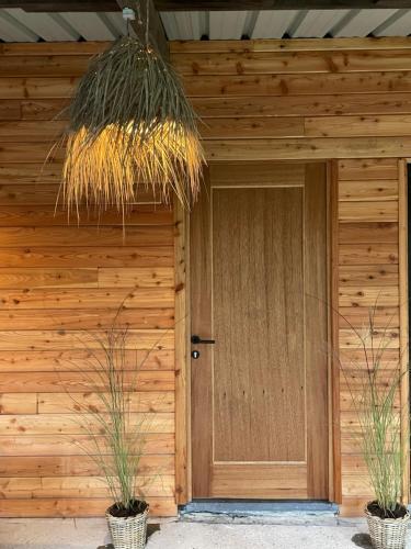 Una casa de madera con una puerta y dos plantas en macetas. en Chez Camille, en Saint-Hubert