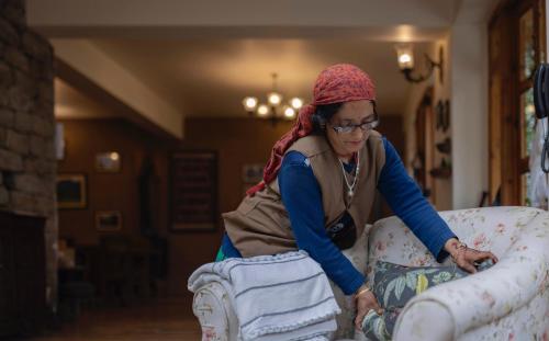 a woman is sitting on top of a couch at Kudrat - A Boutique Homestay- Tirthan Valley in Banjār