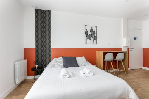 une chambre avec un grand lit blanc avec des murs orange dans l'établissement STUDIOS cosy au centre-ville quartier Jaurès et Saint-Martin, à Brest